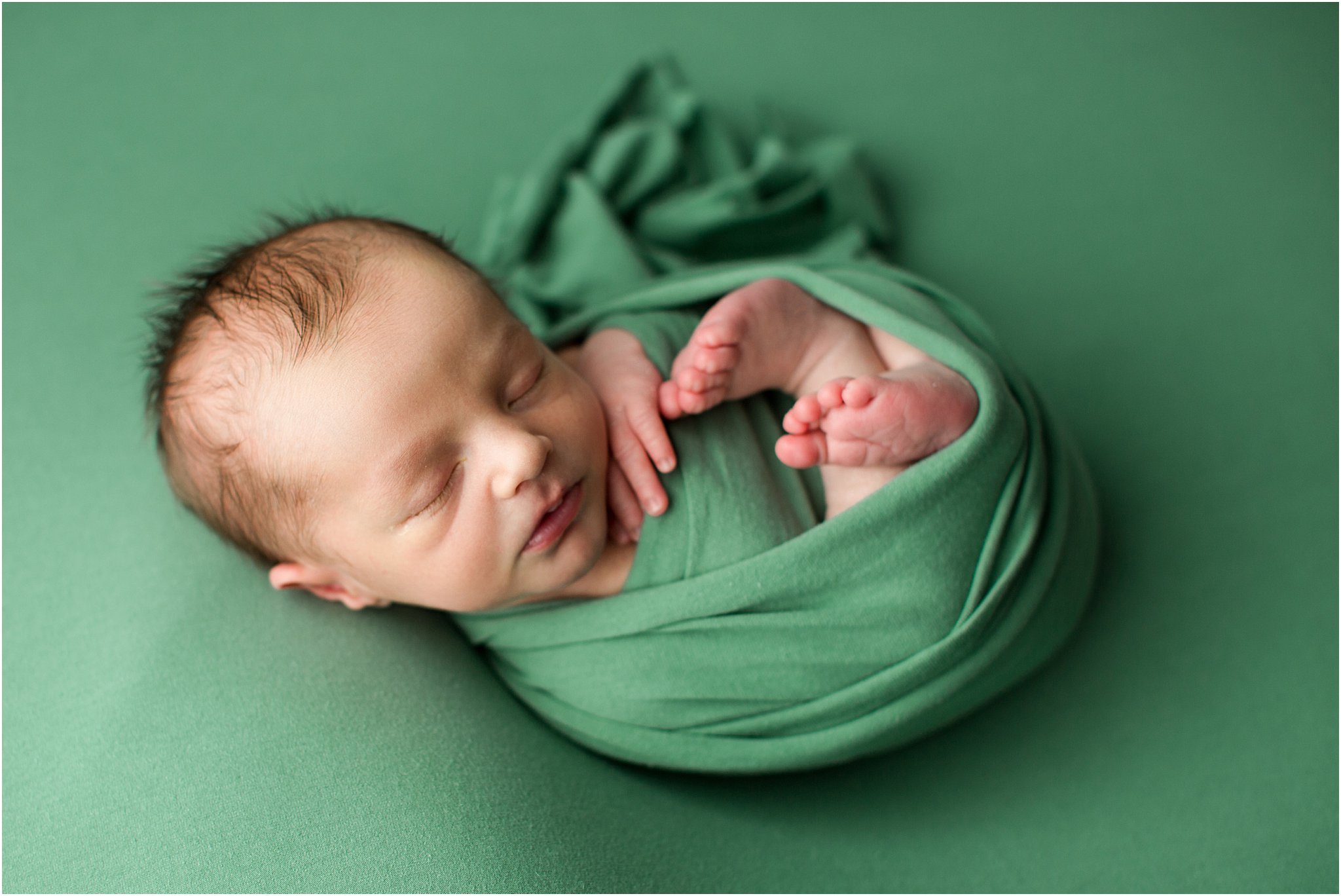 baby wrapped in green 