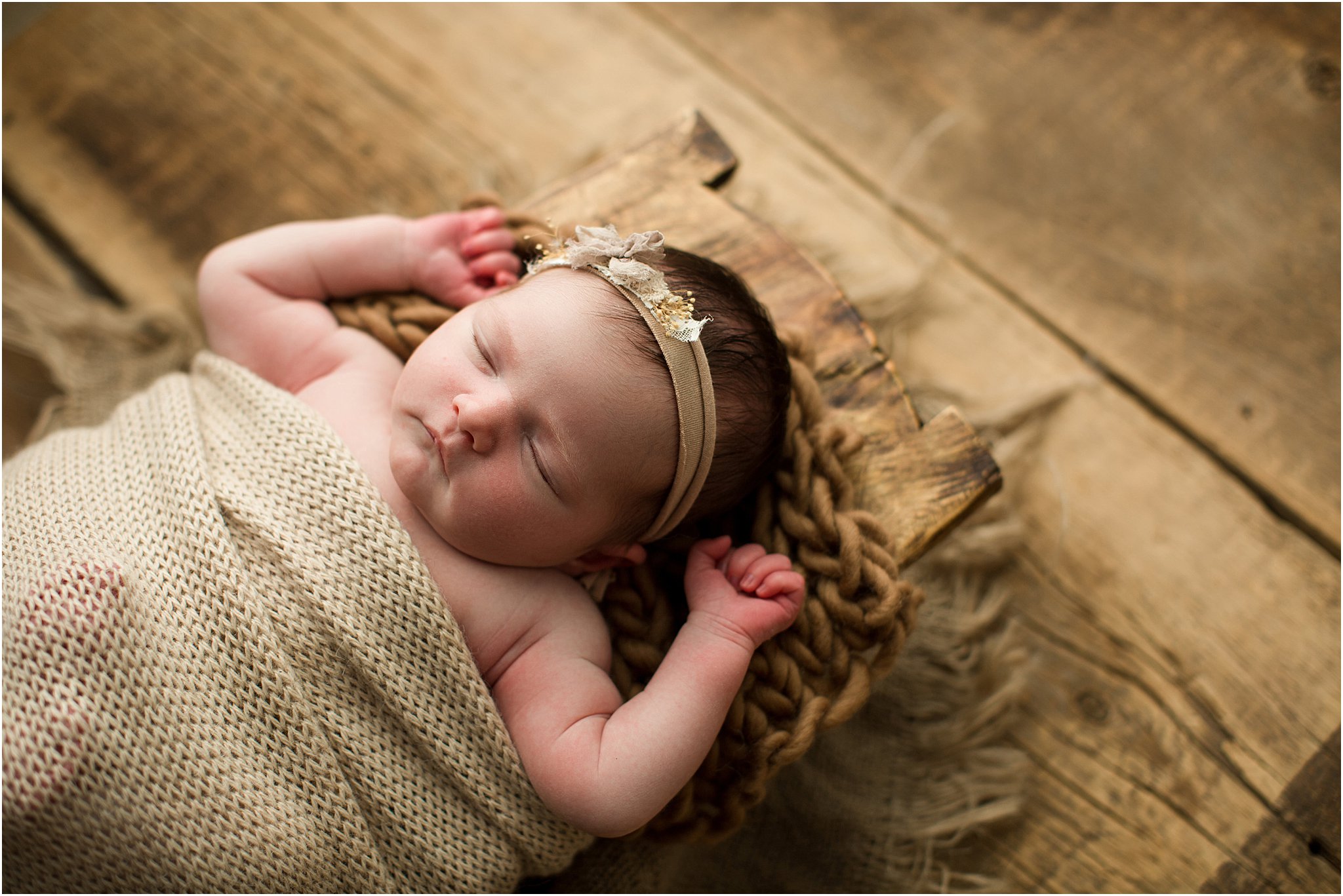 newborn girl in wooden prop on barnwood 