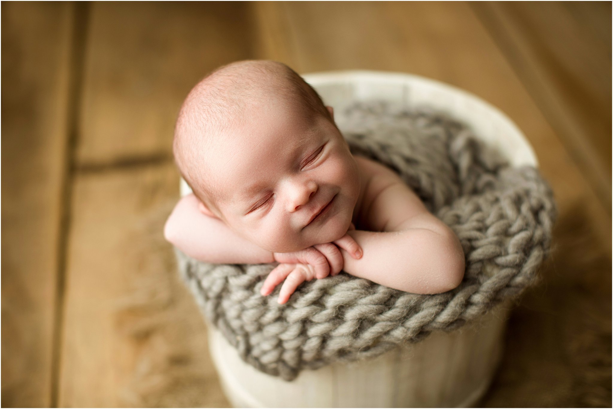 baby boy posed in cream bucket smiling