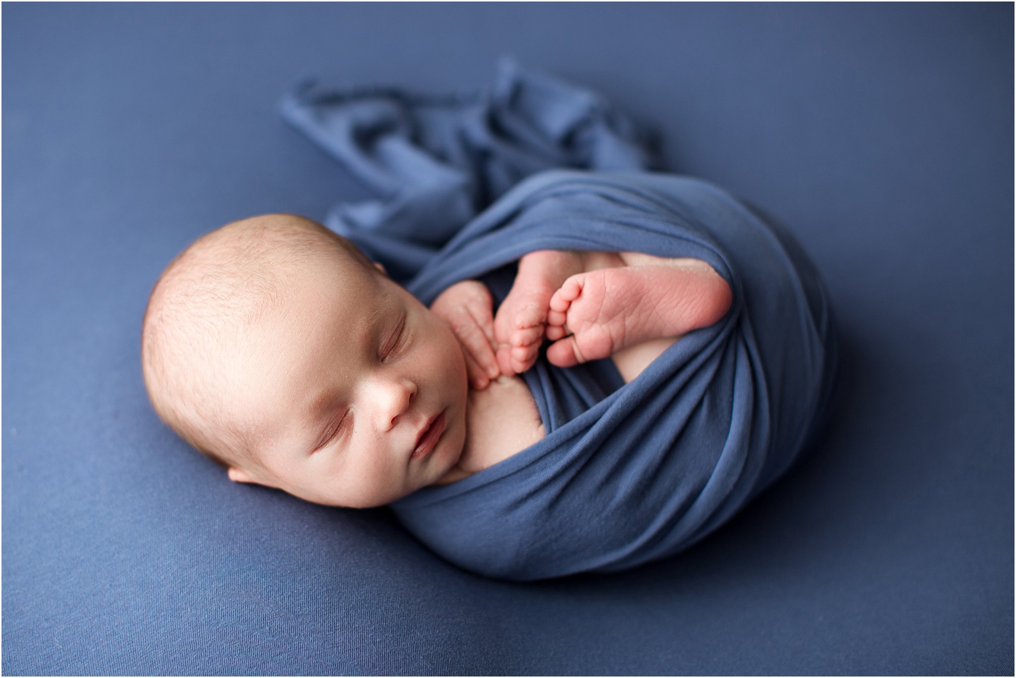 sleeping baby boy wrapped in blue fabric