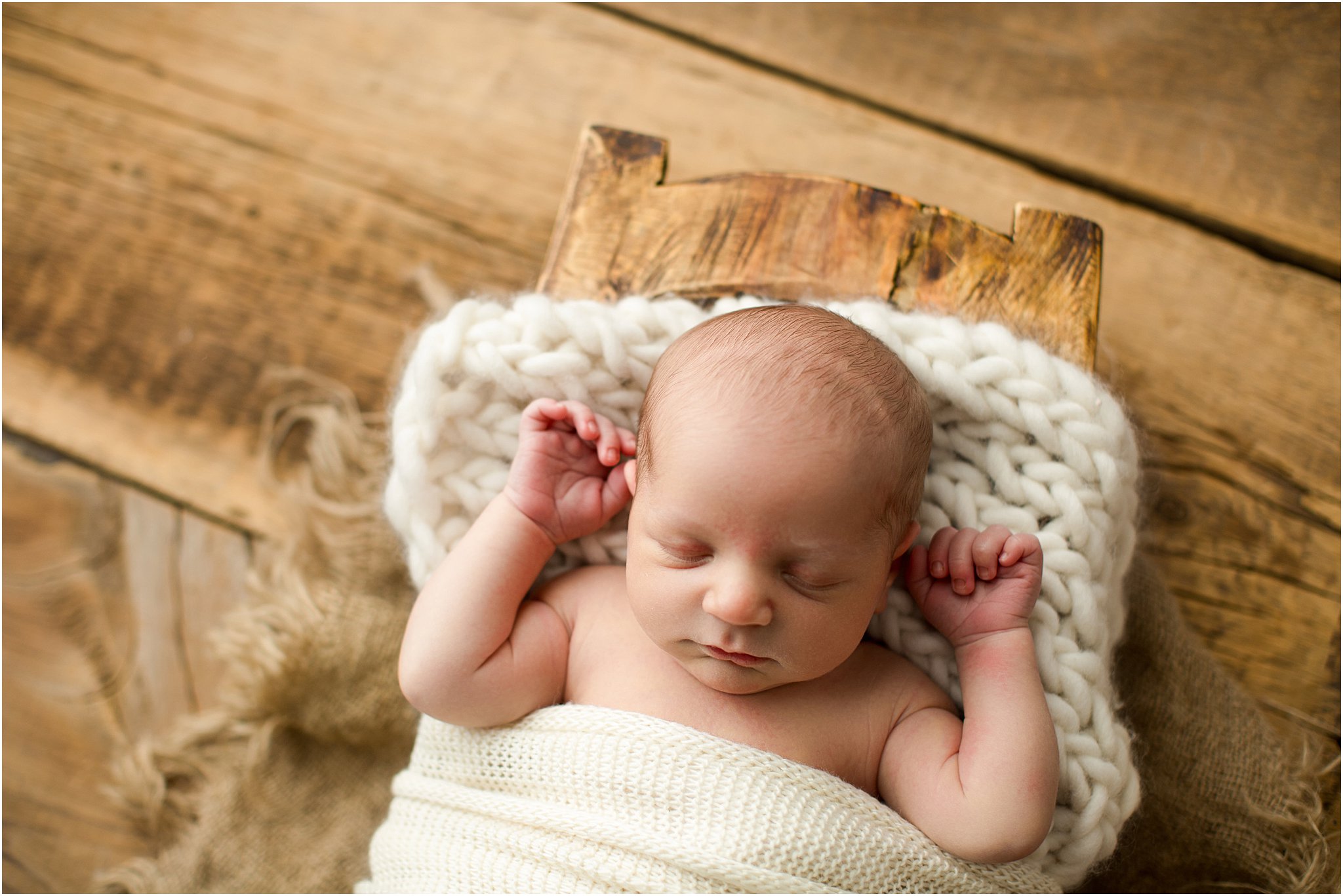 baby boy wrapped in cream knits on barnwood