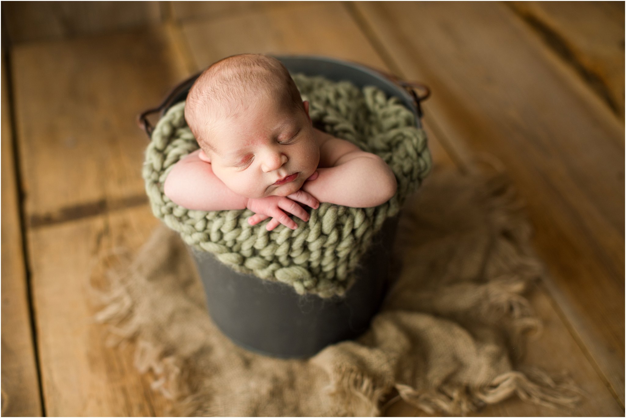 newborn boy posed in bucket on barnwood