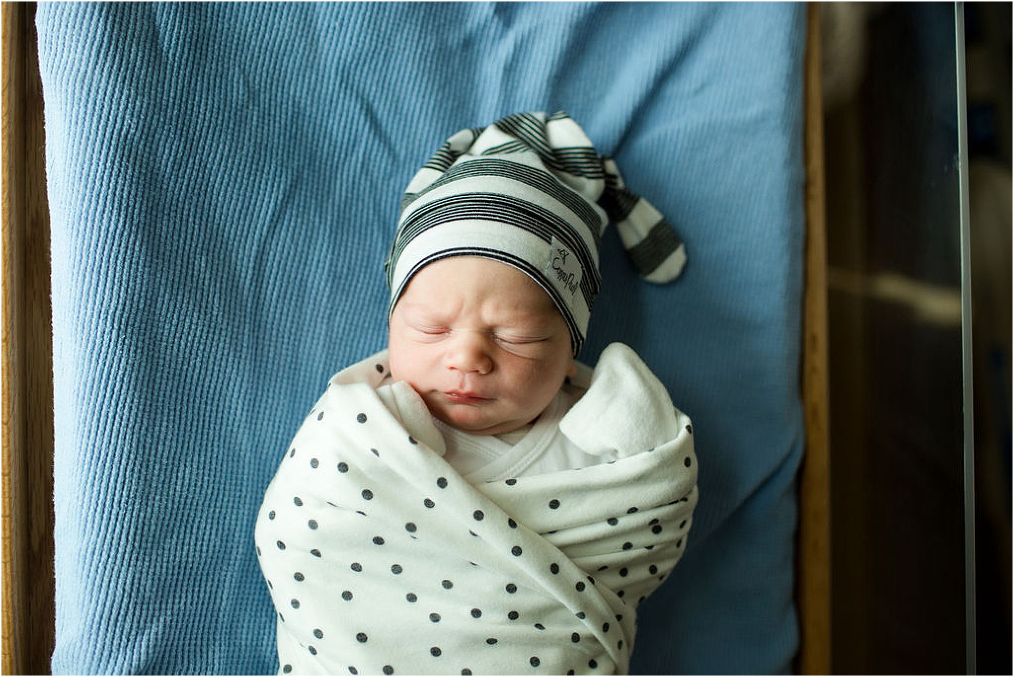 baby boy with striped hat swaddled