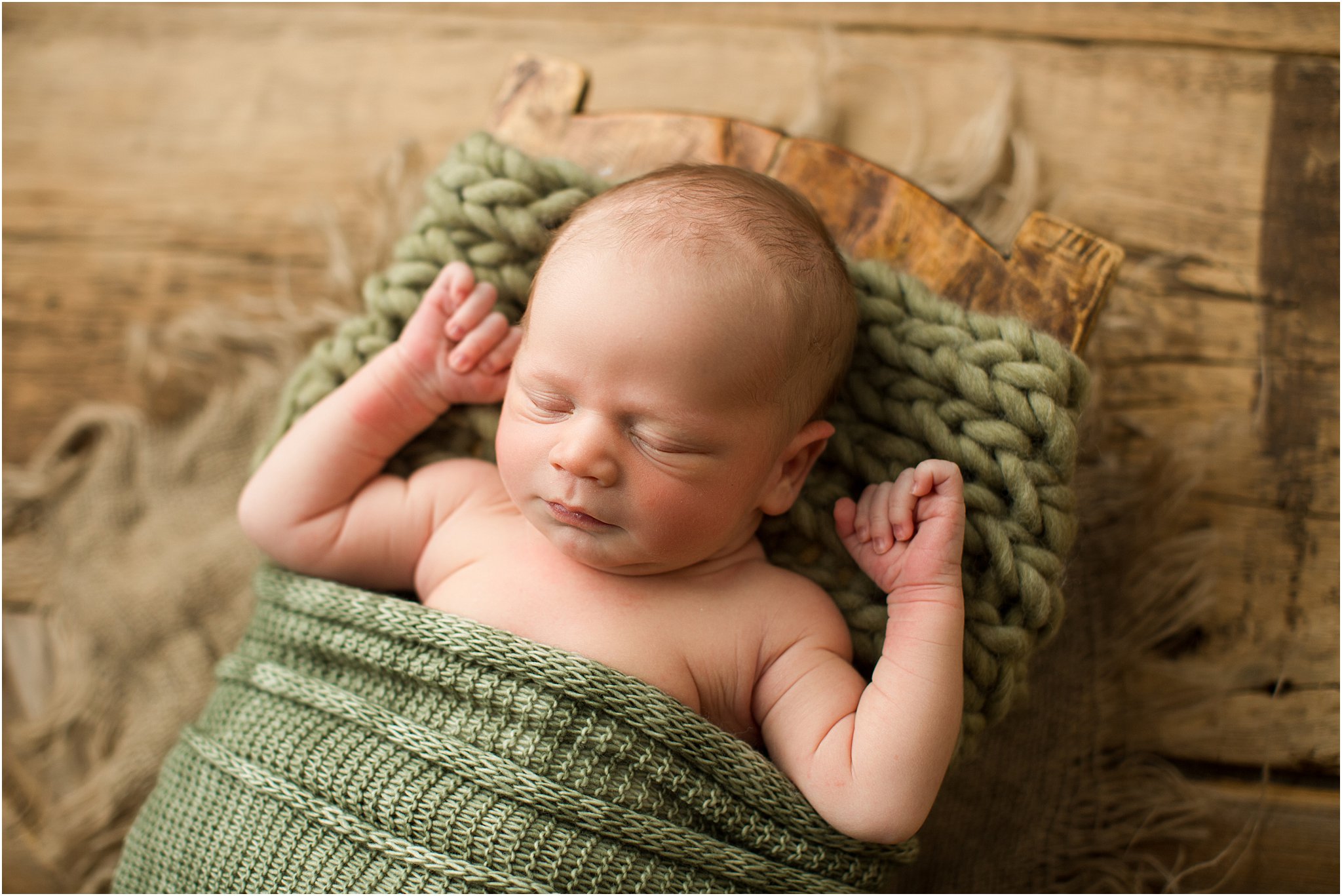 baby boy in green knits and wooden prop