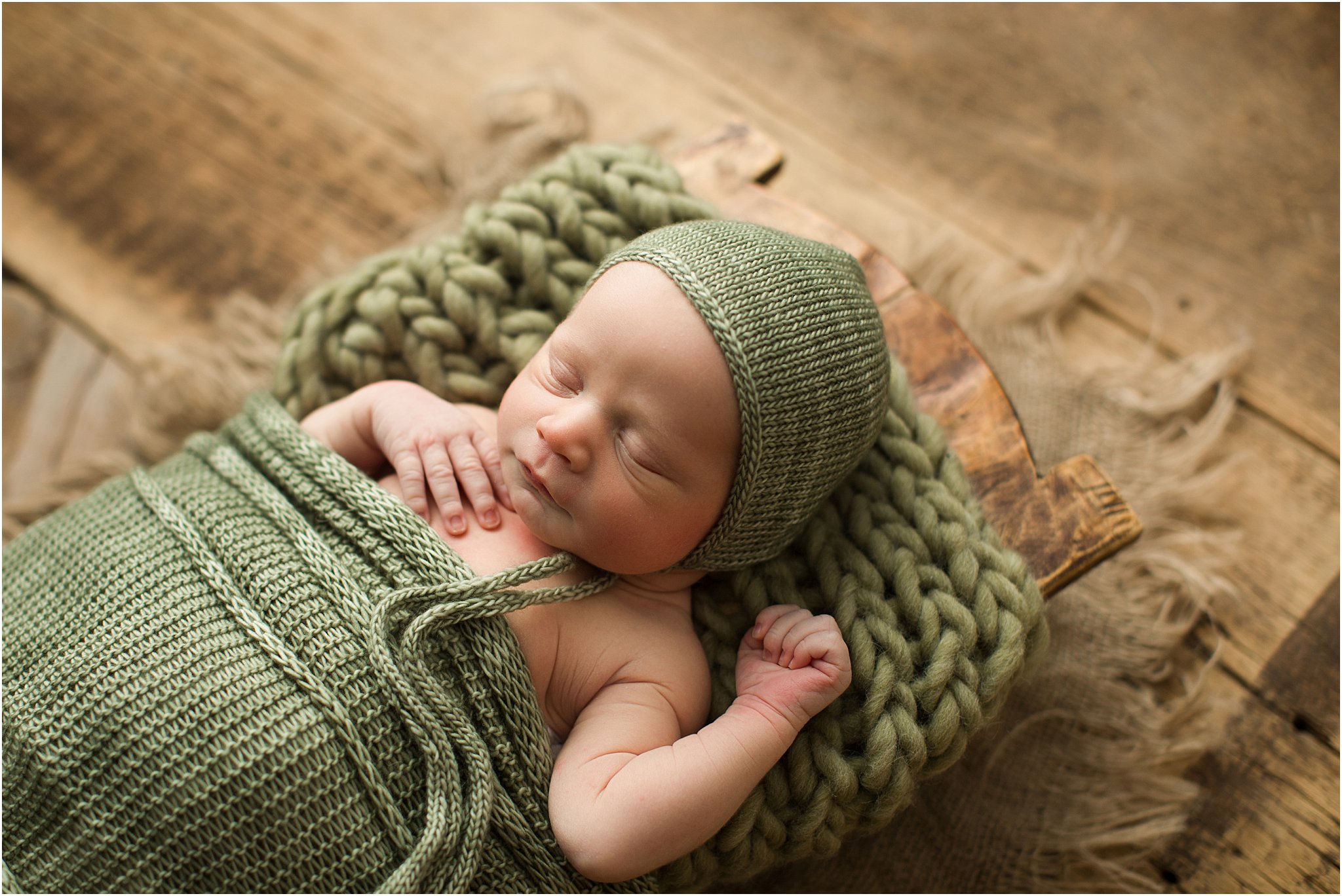 newborn boy wrapped in green with a bonnet