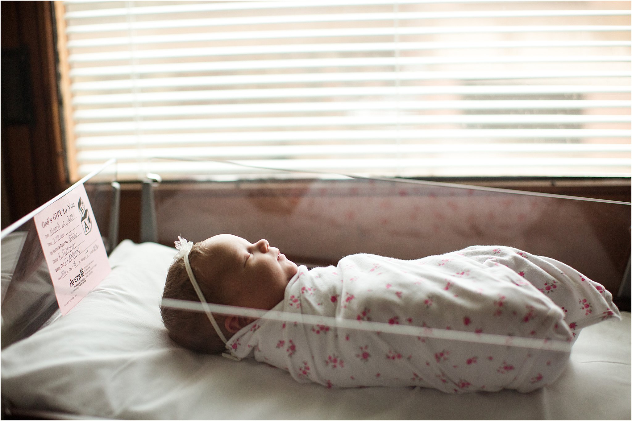 newborn baby girl swaddled in hospital bassinet