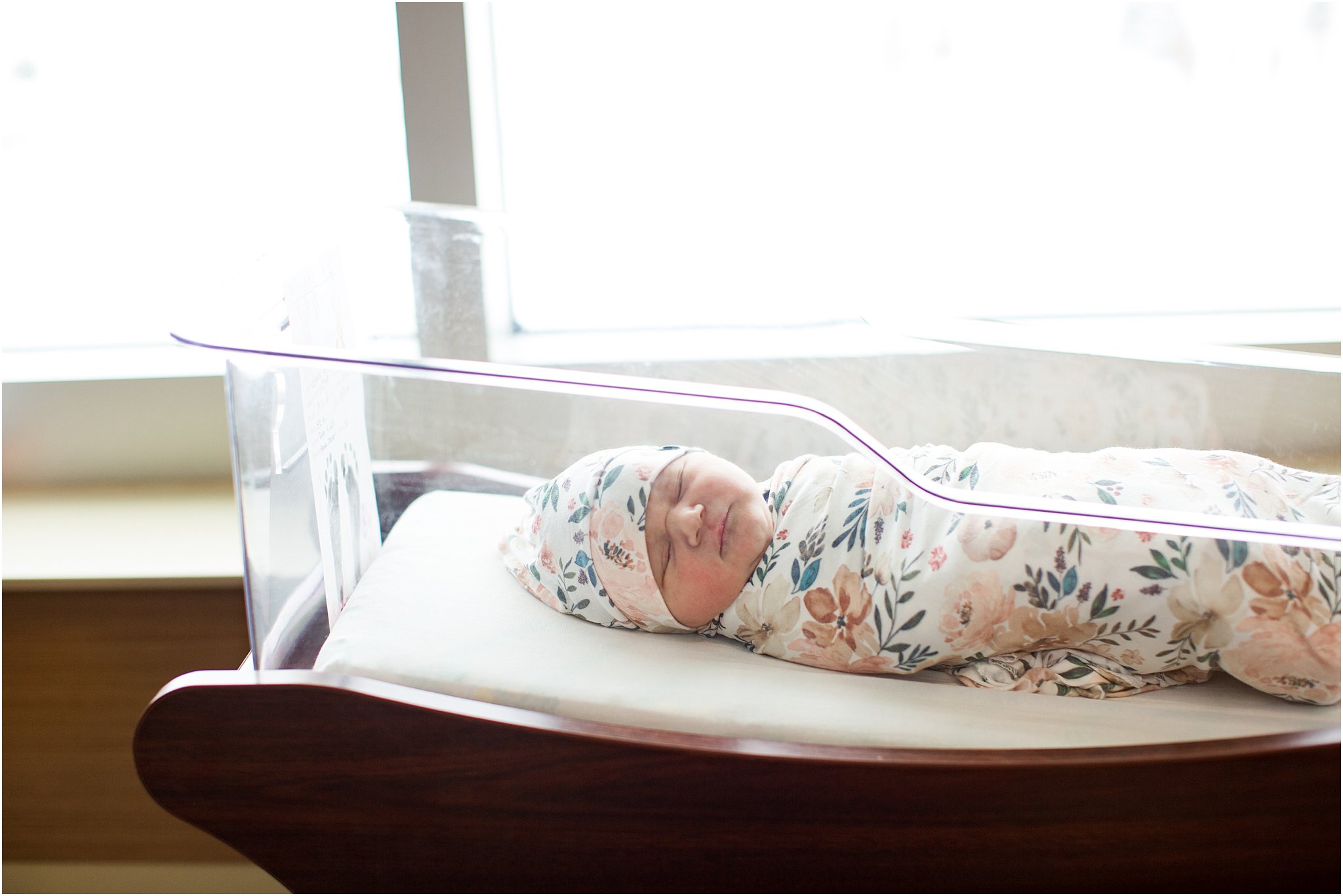 newborn girl in hospital bassinet by window