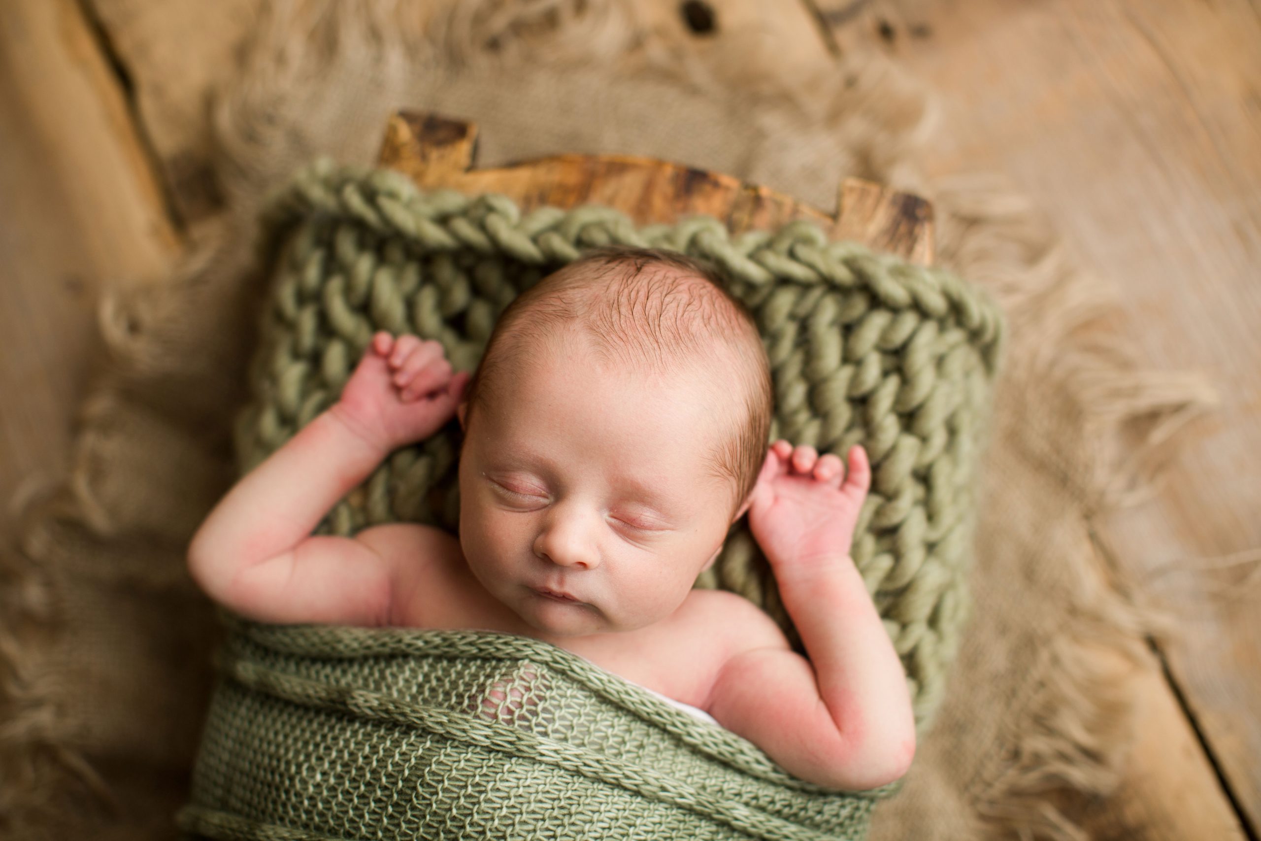 baby boy wrapped in green knits on barnwood
