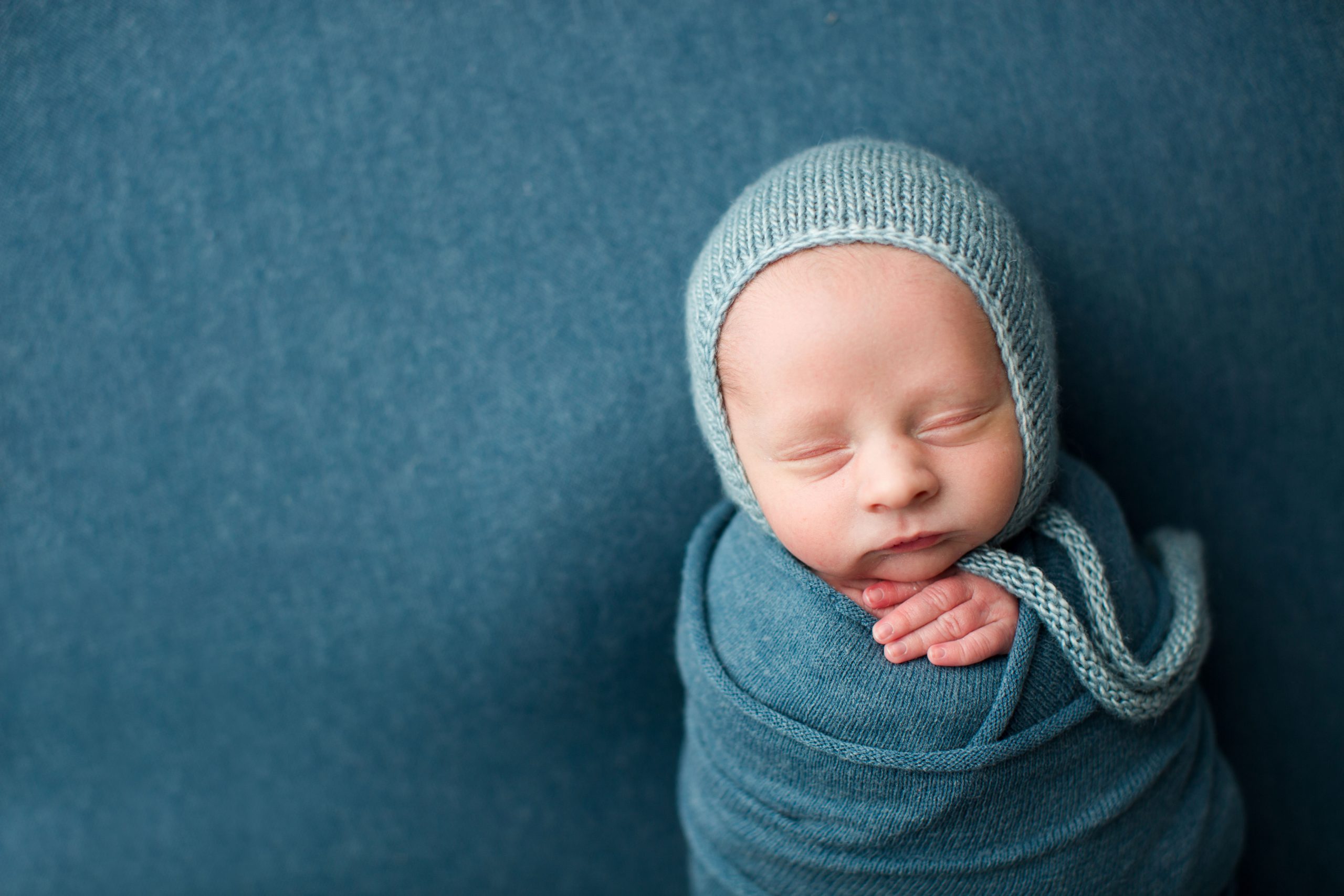 newborn boy wrapped in blue with bonnet