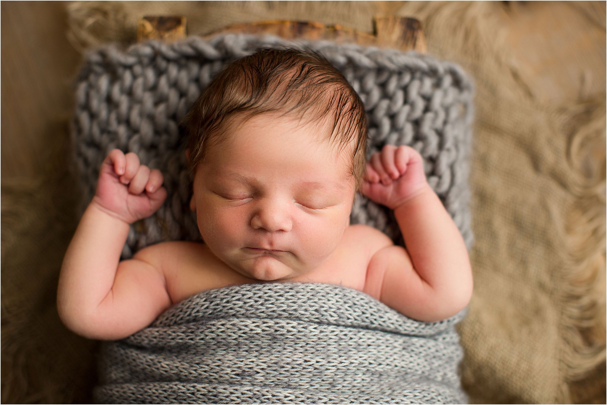 chubby newborn boy wrapped in gray knit layer