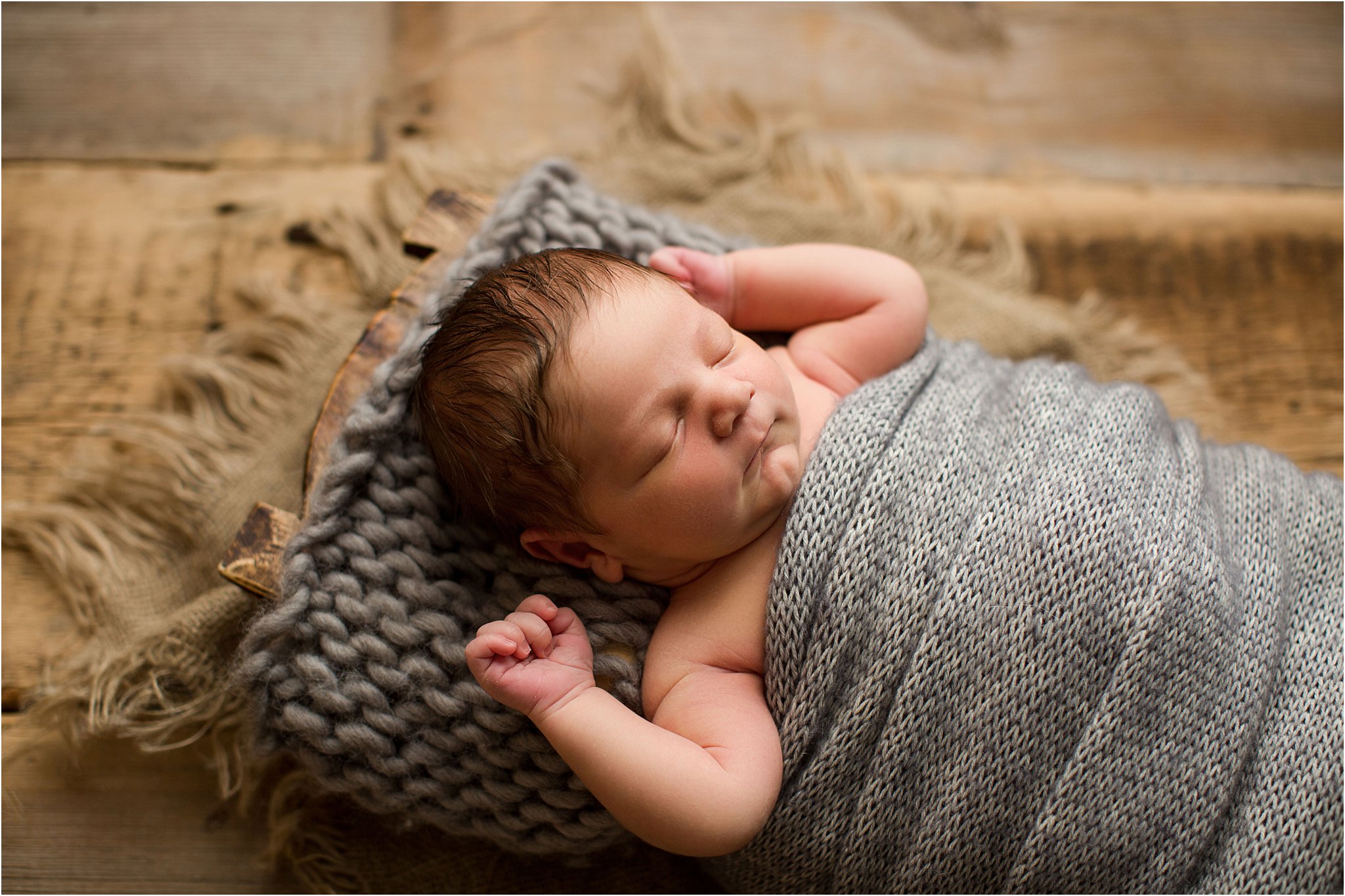 sleeping baby boy wrapped in gray knit wraps