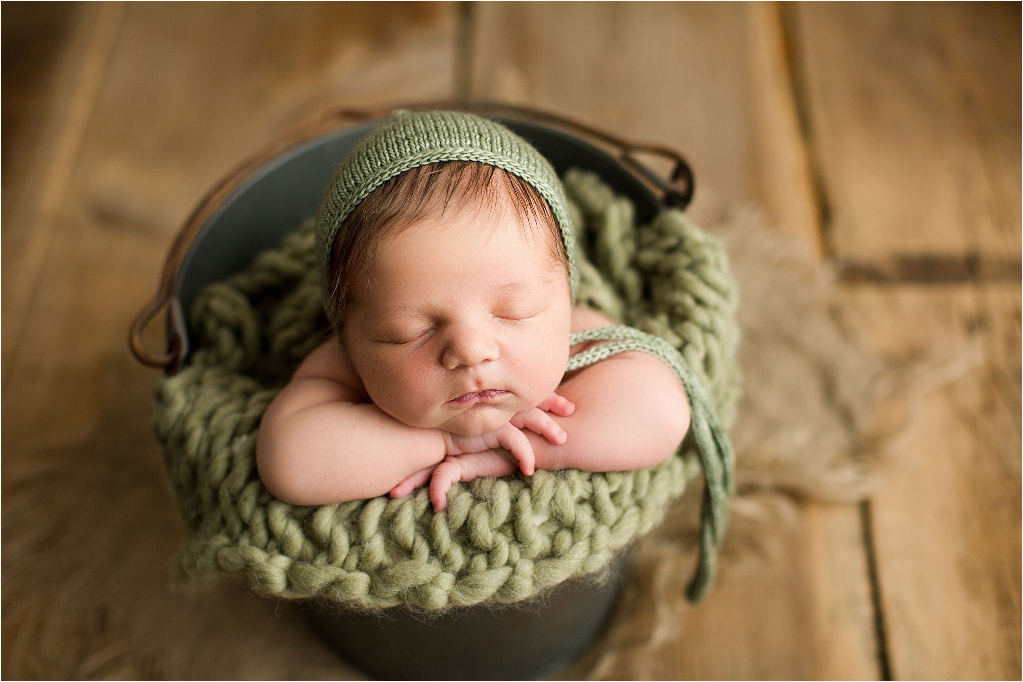 newborn boy in bucket with knit bonnet