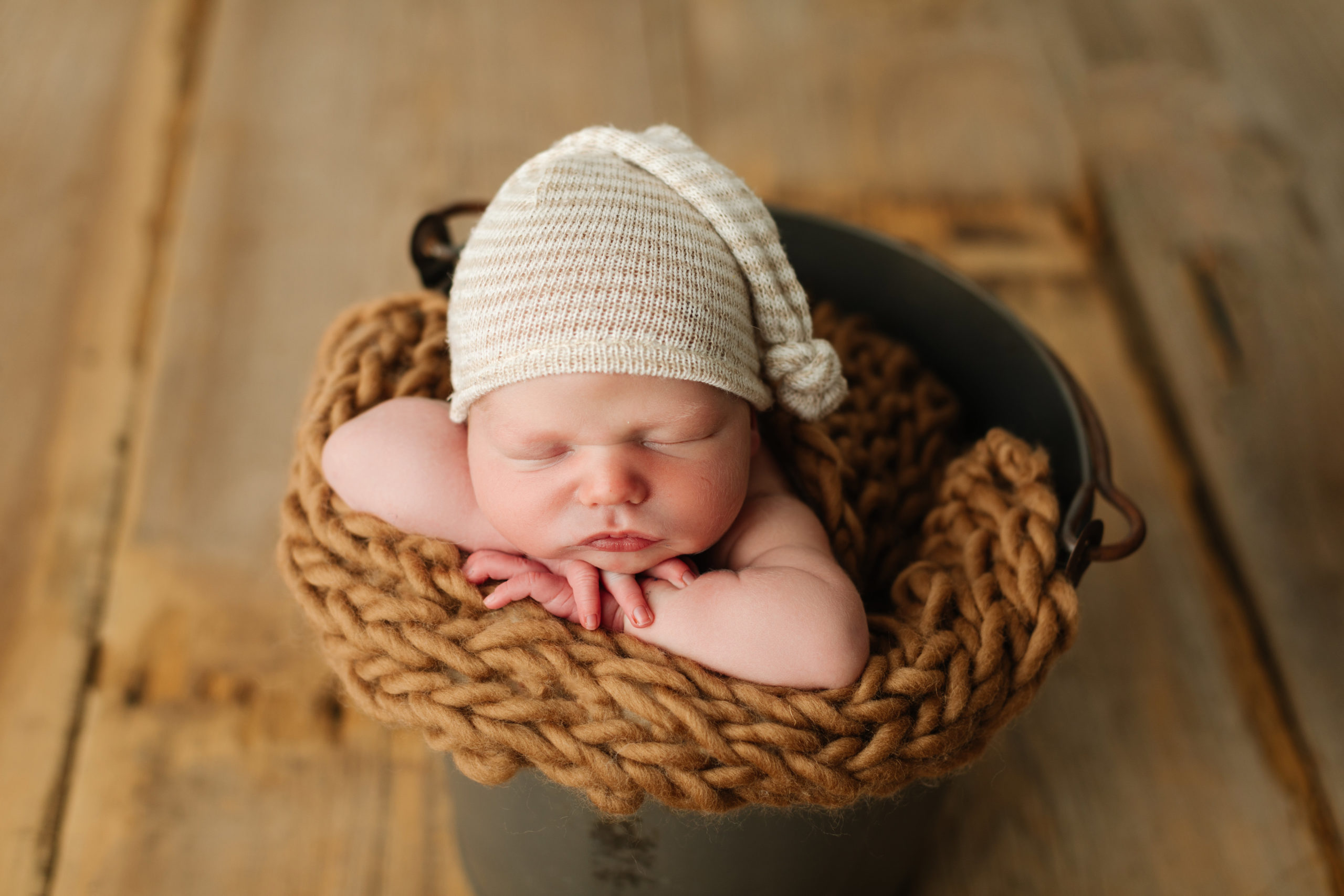 sleepy baby in bucket with knotted hat